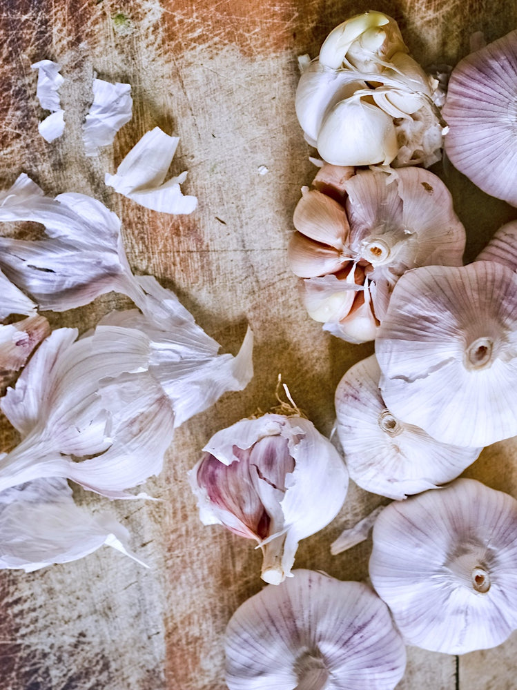 Taiga Farm and Seed Seven Garlic Bulbs on a Cutting Board with Some peeled